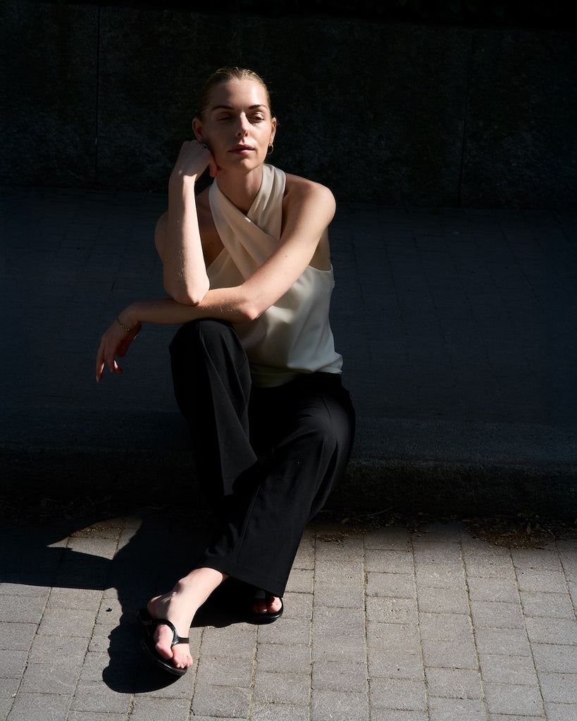 Woman sitting on a stone pavement against a dark wall